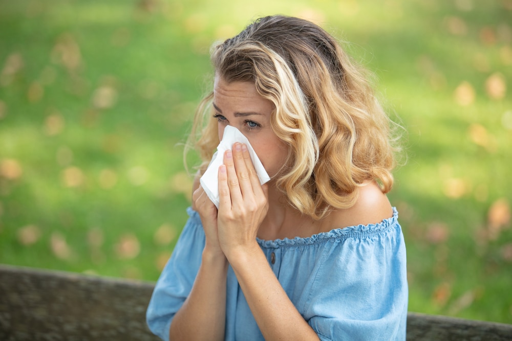 woman with allergies outside in the spring that needs to see allergy doctor